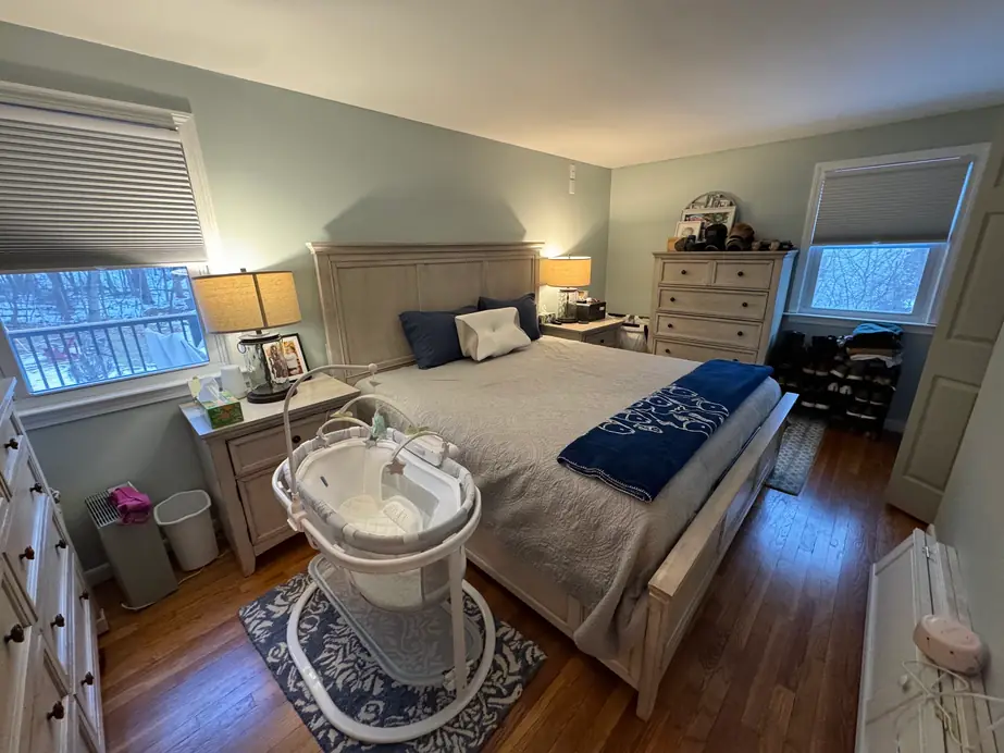 A tidy bedroom with a made bed and a bassinet beside it
